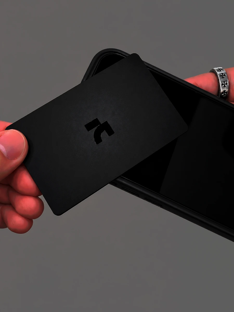 A matte black AnimaNext card held against the back of a phone to activate it